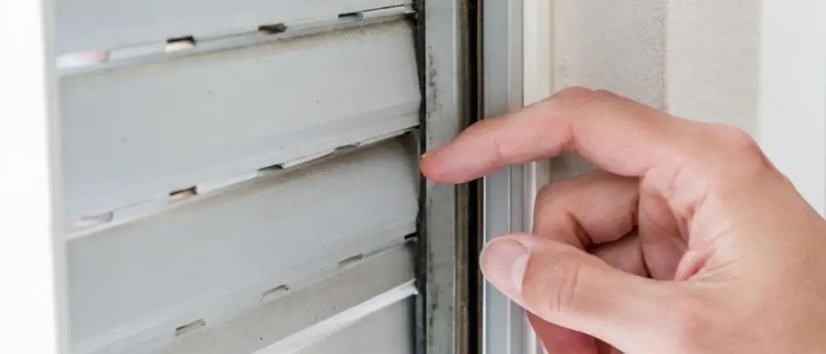Doigts vérifiant l’emboîtement des lames d’un volet roulant dans la coulisse